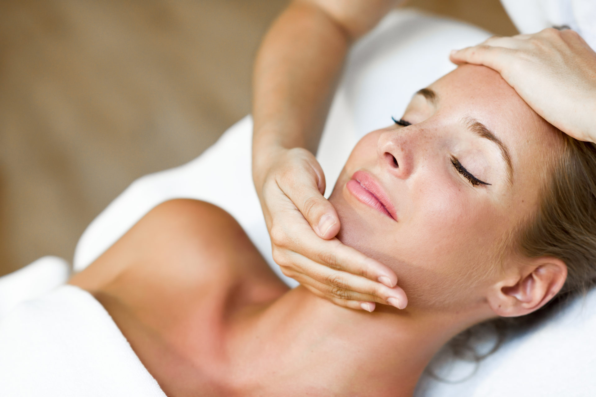 Young woman receiving a head massage in a spa center. Young blond woman receiving a head massage in a spa center with eyes closed. Female patient is receiving treatment by professional therapist.